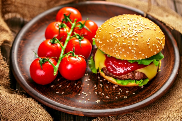 Appetizing burger with tomatoes on table