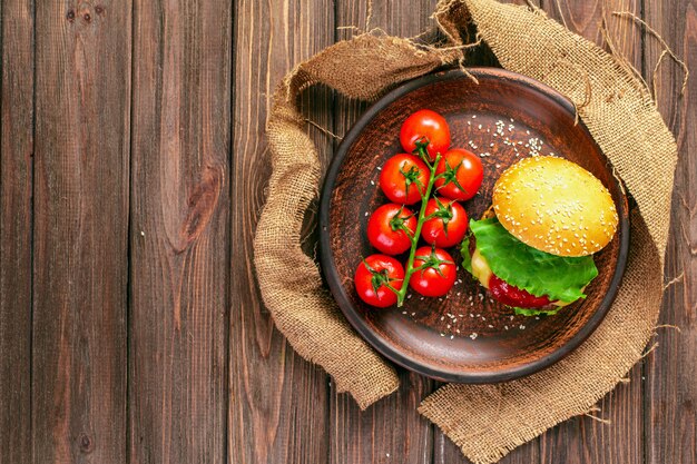 Appetizing burger with tomatoes on table