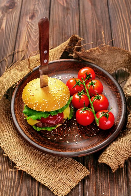 Appetizing burger with tomatoes on table