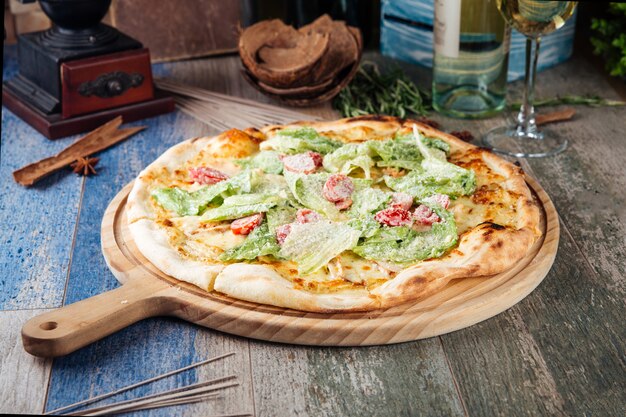 Appetizing caesar pizza with tomatoes and lettuce