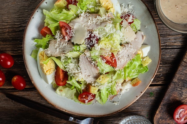 Photo appetizing caesar salad in a plate on a wooden table