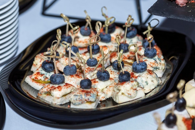 Appetizing cheese canapes with blueberries on a buffet table Catering for holidays and celebrations Closeup