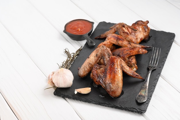 Appetizing chicken wings grilled barbecue with spices and vegetables until crisp