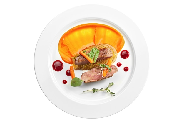 Appetizing confit duck breast with pear and yellow apple puree, berry sauce in a white plate. Isolated on white surface. View from above