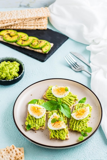 Appetizing crispy bread sandwiches with avocado and boiled egg on a plate Flexitarian diet healthy eating Vertical view