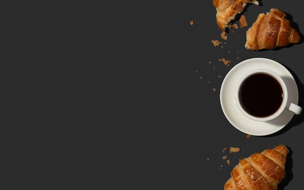검정색 배경에 커피와 함께 식욕을 돋우는 크루아상