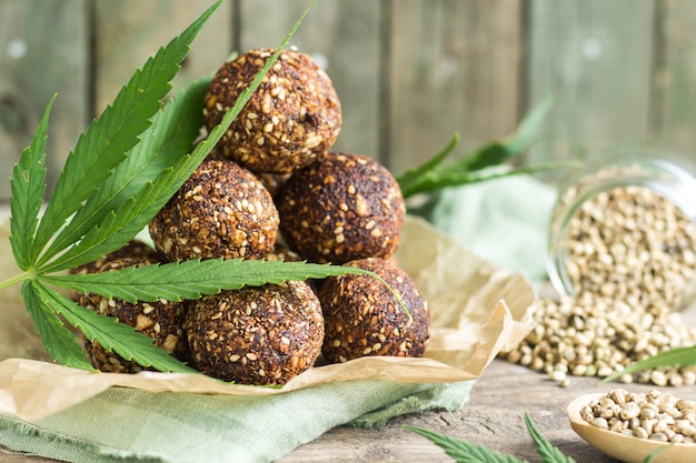 Foto appetitose palline energetiche e semi di cannabis e foglie verdi cotte di muesli, prugne, noci, avena, datteri.