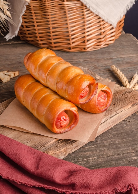 Appetizing fresh culinary pastry - sausages in pastry on wooden background