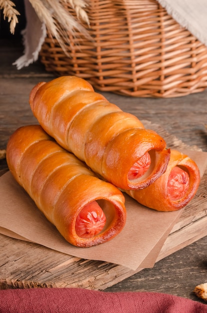 Appetizing fresh culinary pastry - sausages in pastry on wooden background