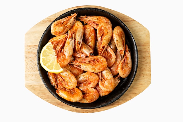 Appetizing fried shrimp with lemon in a serving cast-iron skillet.