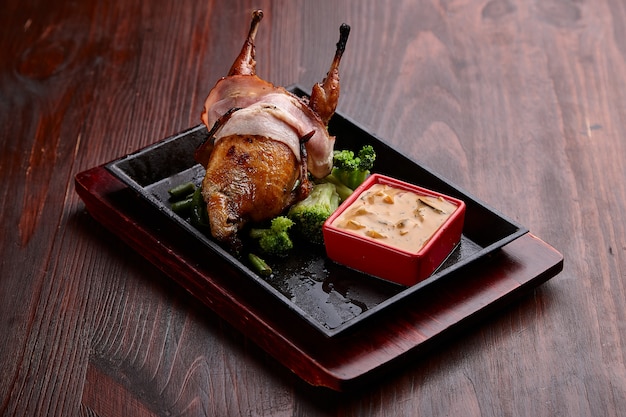 Appetizing grilled meat dishes with sauce on a dark wooden table.