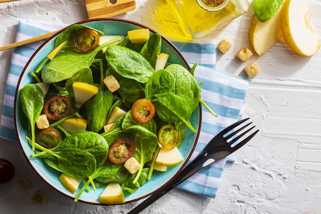 Appetizing and healthy low calorie vegetarian salad with spinach sprouts, fresh apple, tomatoes and toast.