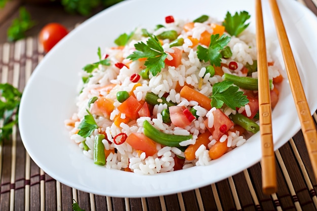 Аппетитный здоровый рис с овощами в белой тарелке