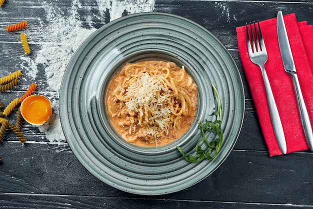 Appetizing homemade pasta bolognese with red sauce and minced meat, parmesan in a blue plate. Close up, top view. Italian spaghetti, photo for the recipe