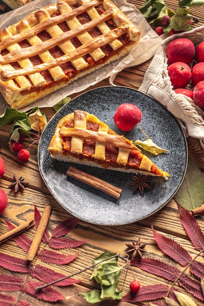 Appetizing homemade pie on a wooden table with garden apples cinnamon and autumn leaves Concept of a cozy atmosphere and autumn mood