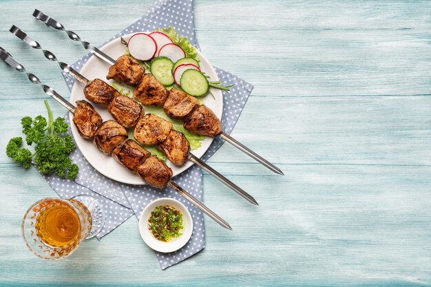 Appetizing homemade shish kebab, sliced vegetables, a glass of wine top view on a blue wooden background.