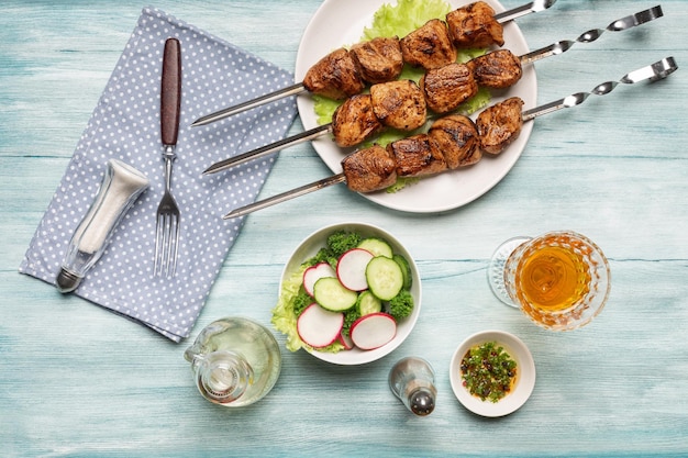 Foto appetitoso shish kebab fatto in casa con verdure a fette un bicchiere di vino vista dall'alto su uno sfondo di legno blu