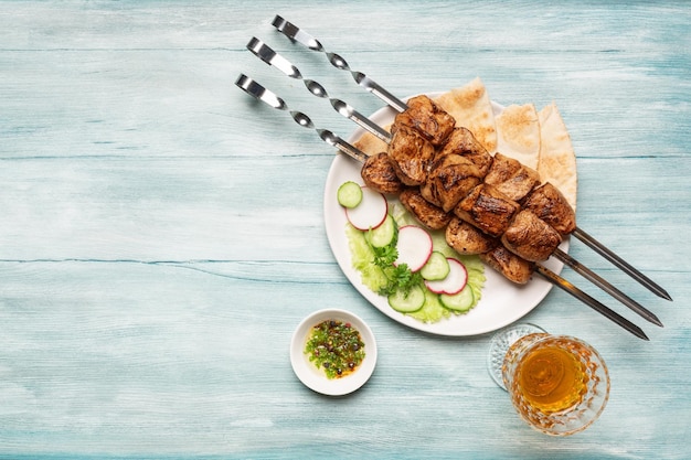 Foto appetitoso shish kebab fatto in casa con verdure a fette un bicchiere di vino vista dall'alto