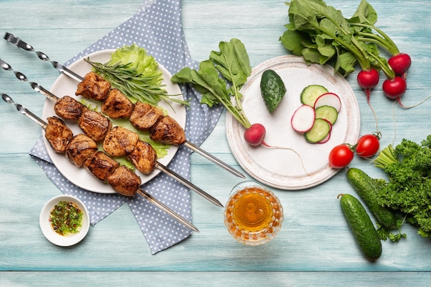 Foto appetitoso shish kebab fatto in casa affettato e verdure intere un bicchiere di vino vista dall'alto