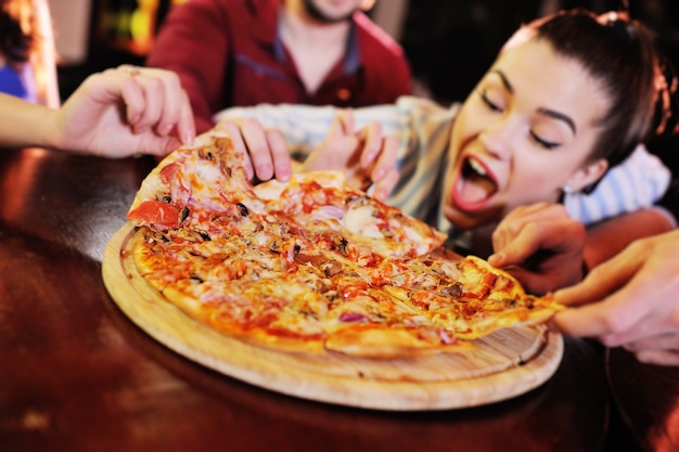 Appetizing hot pizza closeup on a table in the surface of a group or company of people friends