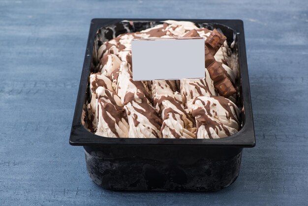 Appetizing ice cream in a plastic container with a price tag on a decorative blue background