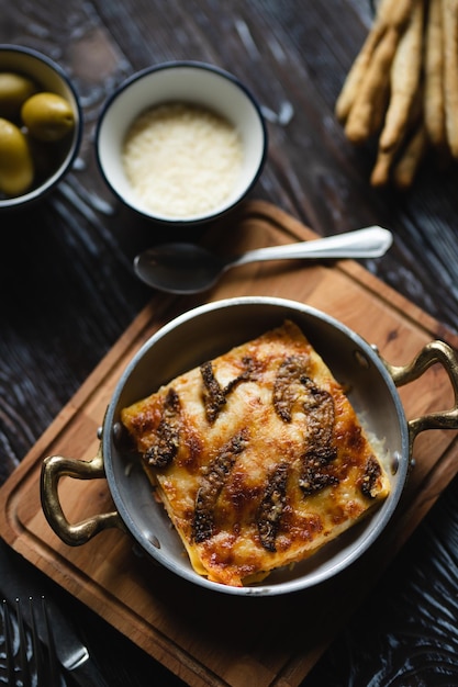 Appetizing lasagna with large olives on a dark background. Food photography