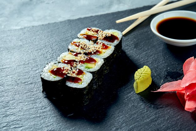 Appetizing maki sushi with avocado on a black slate board