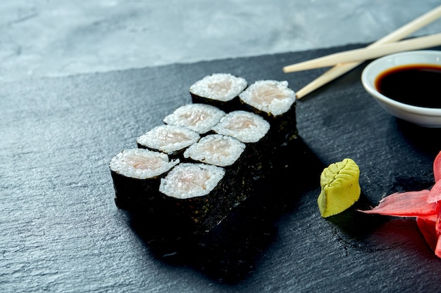 Appetizing maki sushi with perch on a black slate board