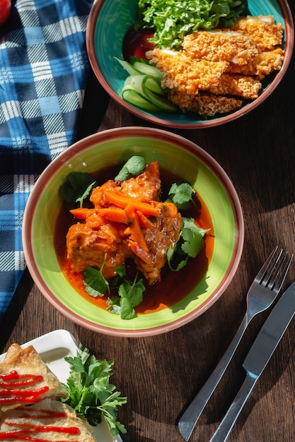 Appetizing meat goulash with sauce (meat and vegetables),\
carrots and cilantro on the table in a beautiful setting, sunny\
lighting