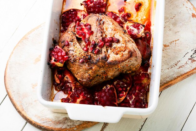 Appetizing piece of pork loin in a fruity marinade Fried meat with pomegranate in baking dish