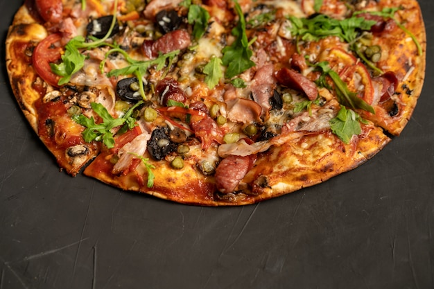 Photo appetizing pizza with smoked sausages bacon meat tomato cheese arugula on black dark . with copyspace