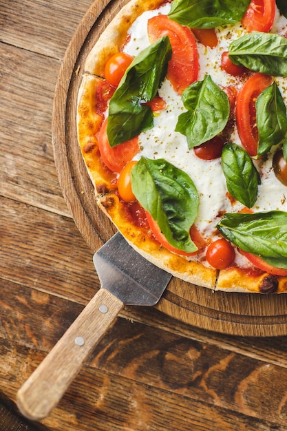 Appetizing pizza with tomatoes and cheese on a wooden background