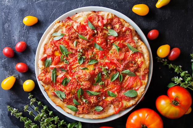 Appetizing pizza with tomatoes on a dark surface