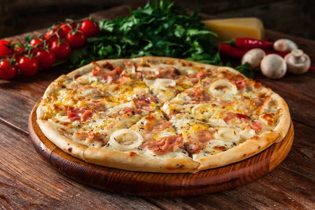 Appetizing pizza on wooden rustic table with ingredients. Traditional italian food, menu photo.