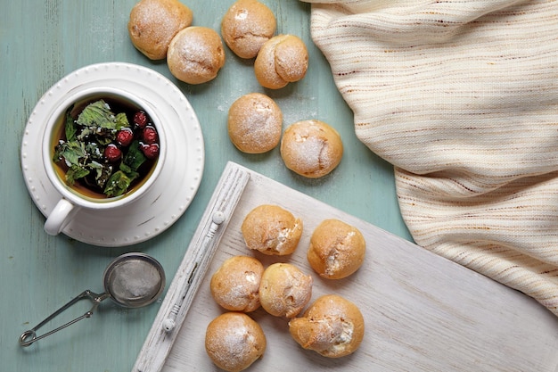 Appetizing profiteroles with whipped cream a cup of herbal tea