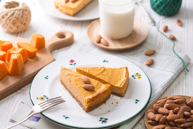 Appetizing pumpkin cheesecake and glass of milk,  almonds