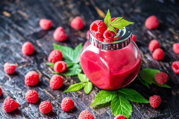 Appetizing raspberry puree in a glass jar and fresh raspberries