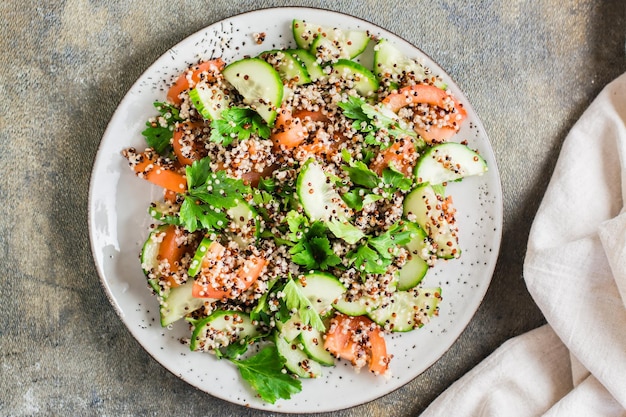 Appetizing salad of cucumbers tomatoes a mixture of quinoa and parsley on a plate on the table Vegetarian food Top view Closeup