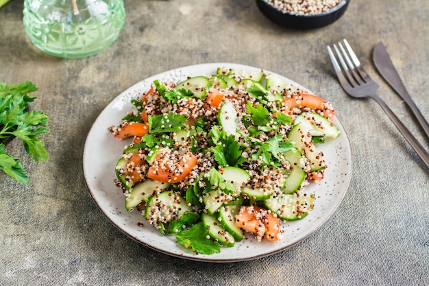 Appetizing salad of cucumbers tomatoes a mixture of quinoa and parsley on a plate on the table Vegetarian food