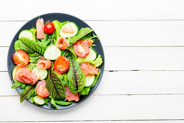 Foto insalata appetitosa con salmone, verdure ed erbe aromatiche.