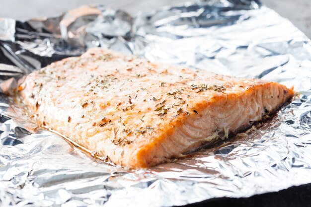 Appetizing salmon steak baked with herbs in aluminum foil