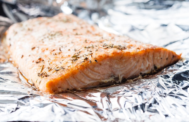 Appetizing salmon steak baked with herbs in aluminum foil