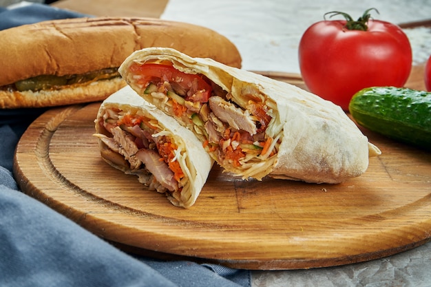 Appetizing shaurma or shawerma with meat, tomato, cabbage. Chicken meat. Kebab on wooden tray. Close up, selective focus