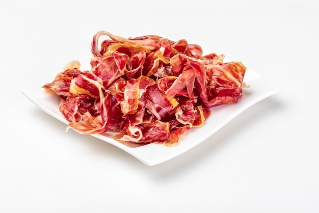 Appetizing slices Iberian ham on a plate. Isolated Raw meat that becomes an article of haute cuisine and gastronomic luxury, through a process of raw salting and natural curing.