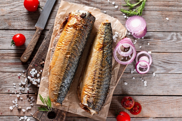 Appetizing smoked fish mackerel, on old dark wooden table background. Top view.