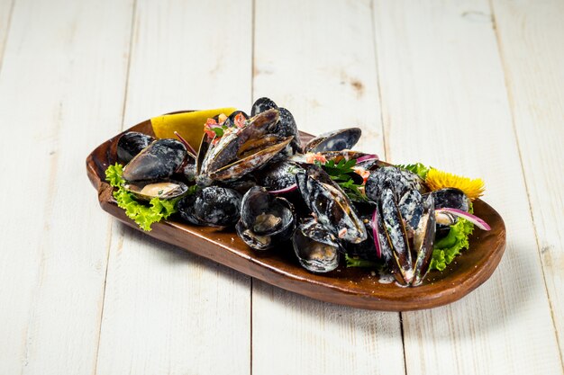 Appetizing stewed mussels in sauce on white background