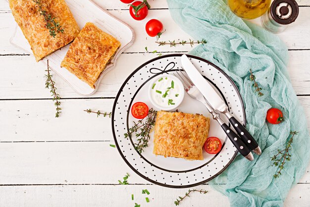 Appetizing strudel with minced beef, onions and herbs. Flat lay. Top view