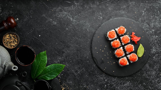 Appetizing sushi rolls with fish and caviar on a black stone plate Japanese cuisine Top view