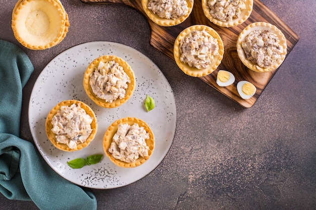 Tartellette appetitose con tonno in scatola di uova e insalata di cipolle su un piatto sulla vista del tavolo