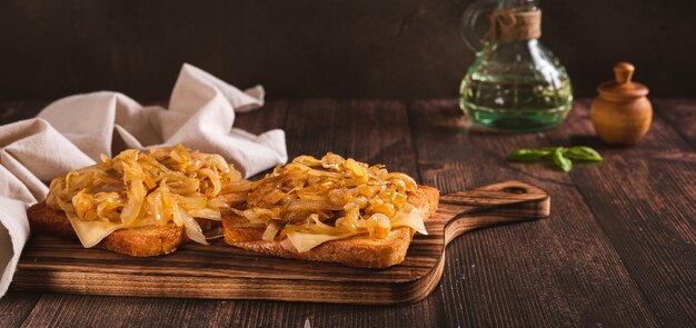 Appetizing toast with melted cheese and caramelized onions on a board web banner